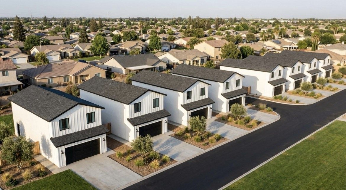 Aerial rendering of the completed community: rows of white board-and-batten homes with dark gabled roofs along a new street within an established Bakersfield neighborhood.