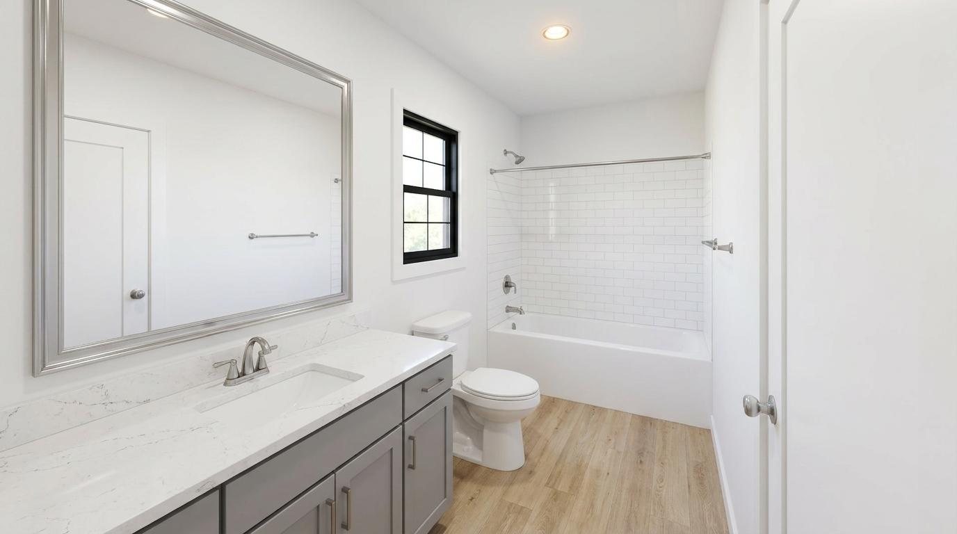 Bathroom photo with a quartz-topped gray vanity, framed mirror, white subway-tiled tub surround and wood-look flooring.
